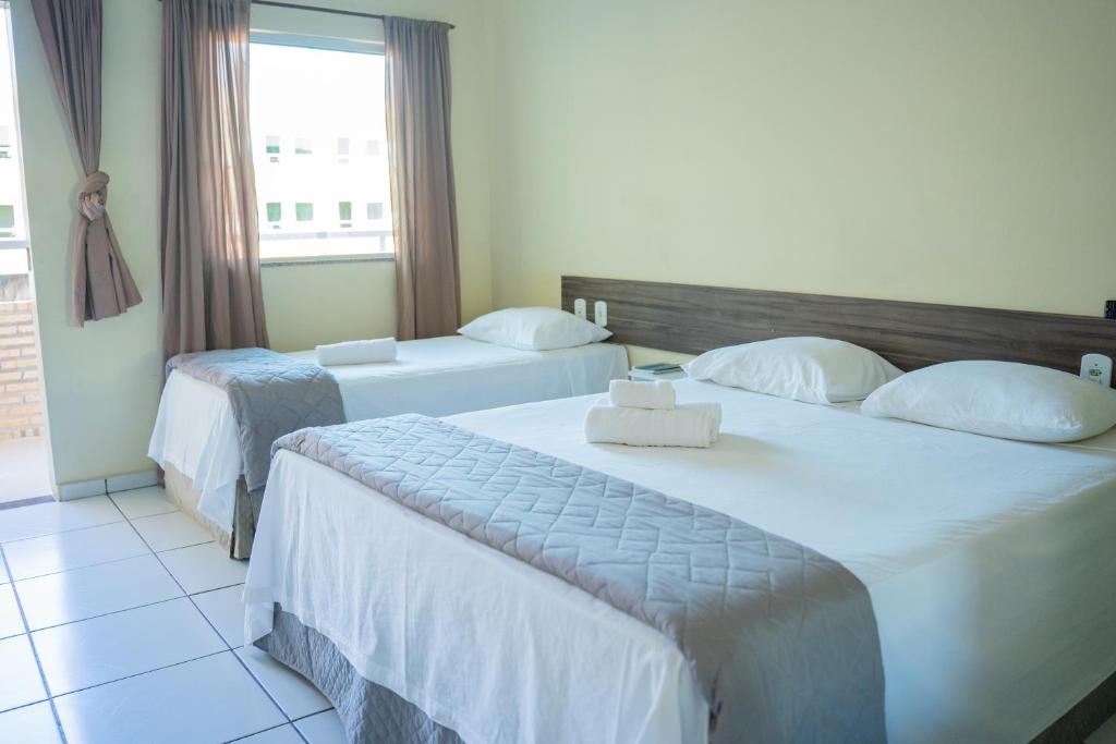 Habitación de hotel con 2 camas y ventana en Pousada Aeroporto en Parnaíba