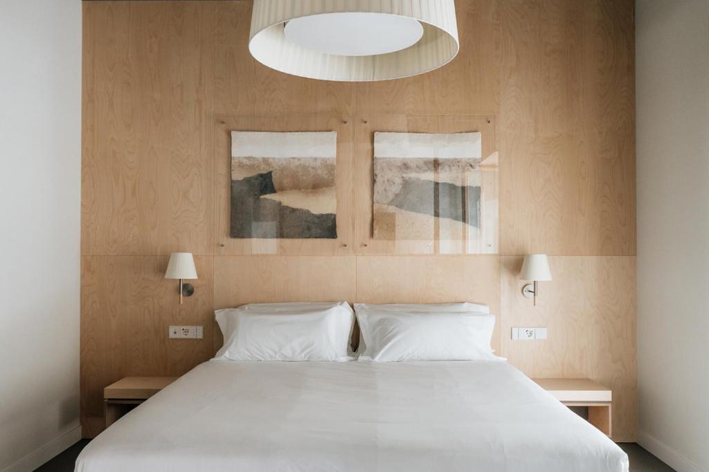 a bedroom with a large white bed with two windows at Hotel Santa Ana Tudela in Tudela