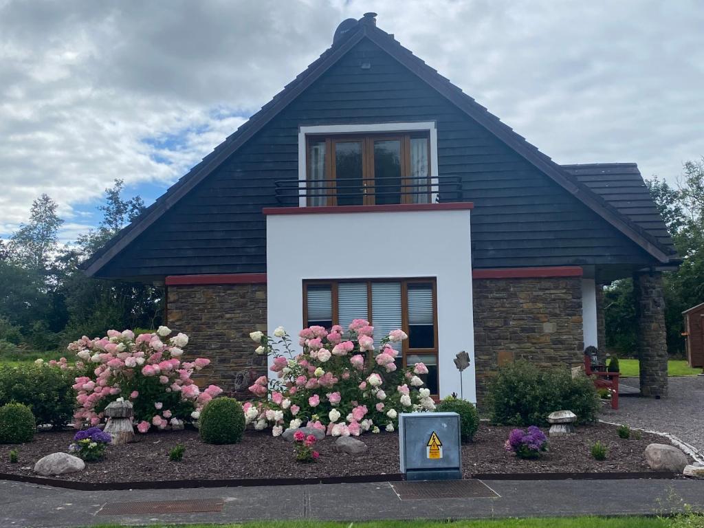 una pequeña casa con flores rosas delante en 2 Caragh Glen en Killorglin