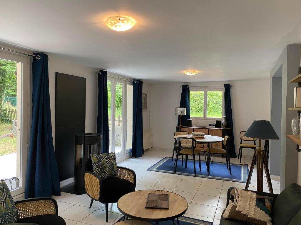 uma sala de estar com cortinas azuis e uma mesa e cadeiras em Maison dans parc privé, sports et loisirs proche golf du Coudray Montceaux em Le Coudray-Montceaux