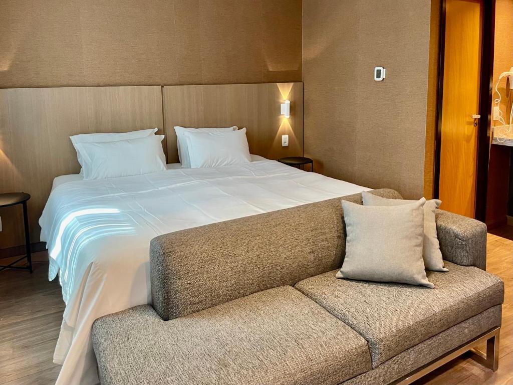 a bedroom with a large bed and a couch at Flat particular incrível no hotel Wynd Ibirapuera antigo B Convention in Sao Paulo