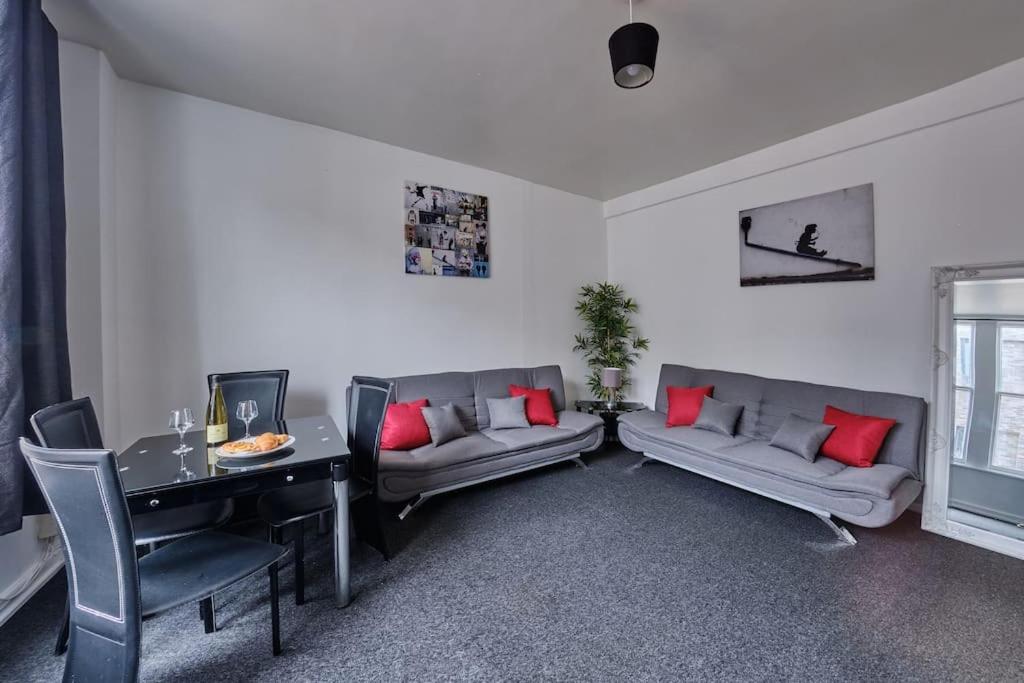 ein Wohnzimmer mit Sofas, einem Tisch und einem Schreibtisch in der Unterkunft Central flat in Basingstoke in Basingstoke