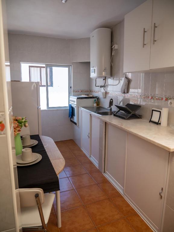 a kitchen with white cabinets and a table and a tableablish at Casa D'Olívia in Carrapateira