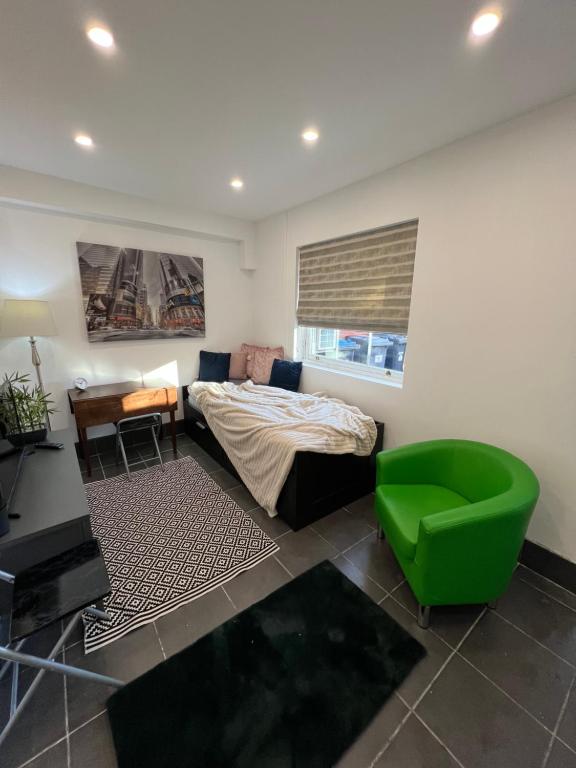 a bedroom with a bed and a green chair at Modern flat in central Egham by Windsor Castle, Staines-Upon-Thames and Heathrow Airport in Egham