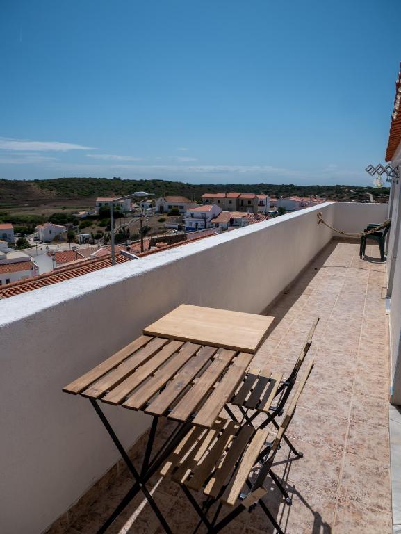 a wooden table and chairs sitting on a balcony at Casa D'Olívia in Carrapateira