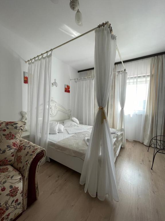 ein Schlafzimmer mit einem Bett mit weißen Vorhängen und einem Sofa in der Unterkunft Hotel Prestige in Alba Iulia