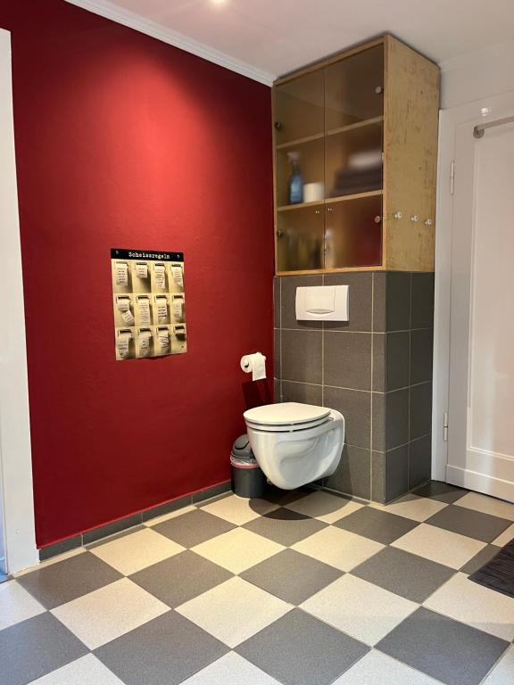 ein Bad mit einem WC und einer roten Wand in der Unterkunft Ferienhaus Brinker Bleibe in Velbert