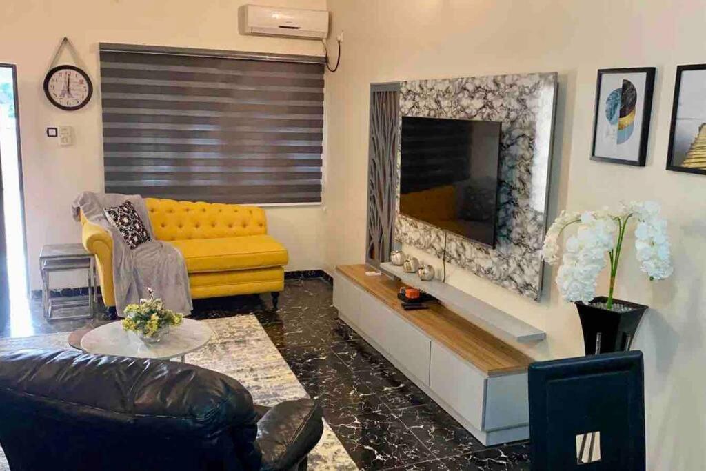 a living room with a yellow couch and a fireplace at Peniel Place in Makurdu