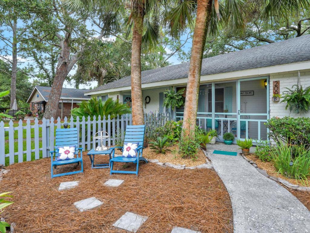 two blue chairs sitting in front of a house at Salt Palms Cottage in Tybee Island