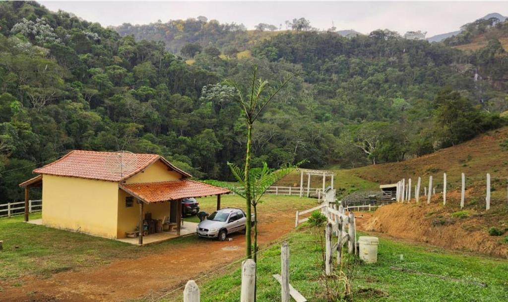 a small yellow house with a car parked next to it at Sitio Cachoeira da Gomeira in Passa Quatro