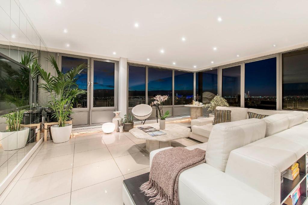 a living room with white furniture and large windows at The OMG penthouse in London