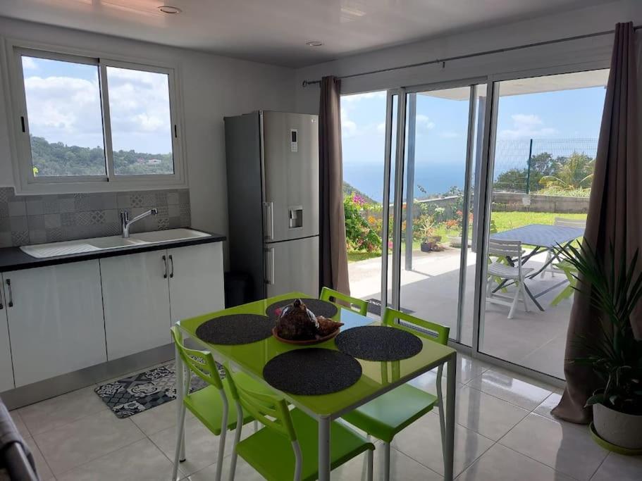 a kitchen with a green table and chairs with a view at Citronnelles in Case-Pilote