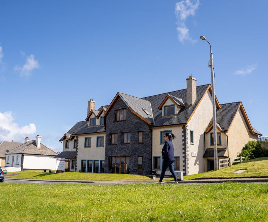 un homme marchant devant une maison dans l'établissement Waterfront House & Restaurant, à Enniscrone