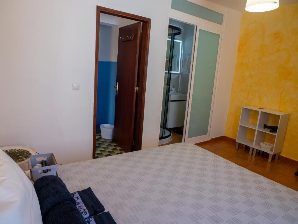 a bedroom with a bed and a door to a bathroom at Casa D'Olívia in Carrapateira