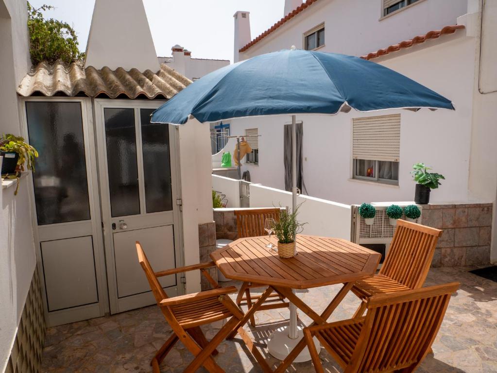 a table and chairs with a blue umbrella on a patio at Casa D'Olívia in Carrapateira