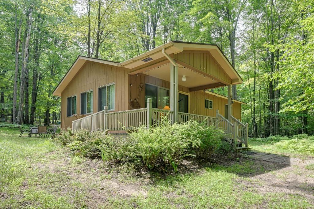 a tiny house in the woods with a porch at Secluded Farwell Cabin with Fire Pit and Gas Grill! in Lake