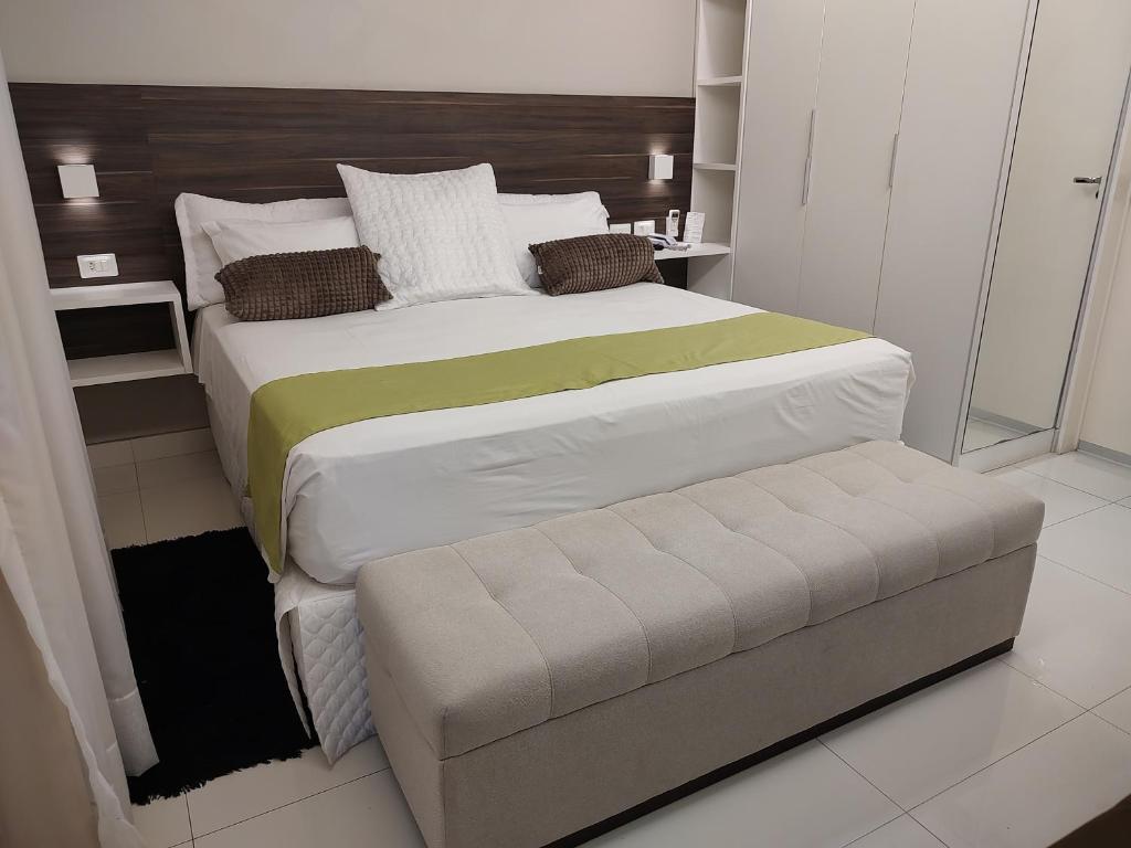 a bedroom with a large bed and a bench at Hotel Jucazinho in Surubim