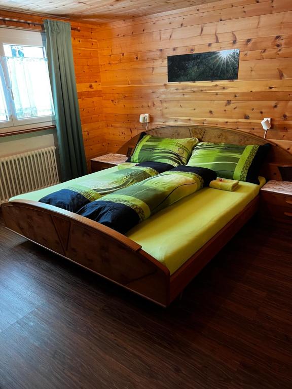 een groot bed in een kamer met een houten muur bij Haus Bergkristall in Herbriggen