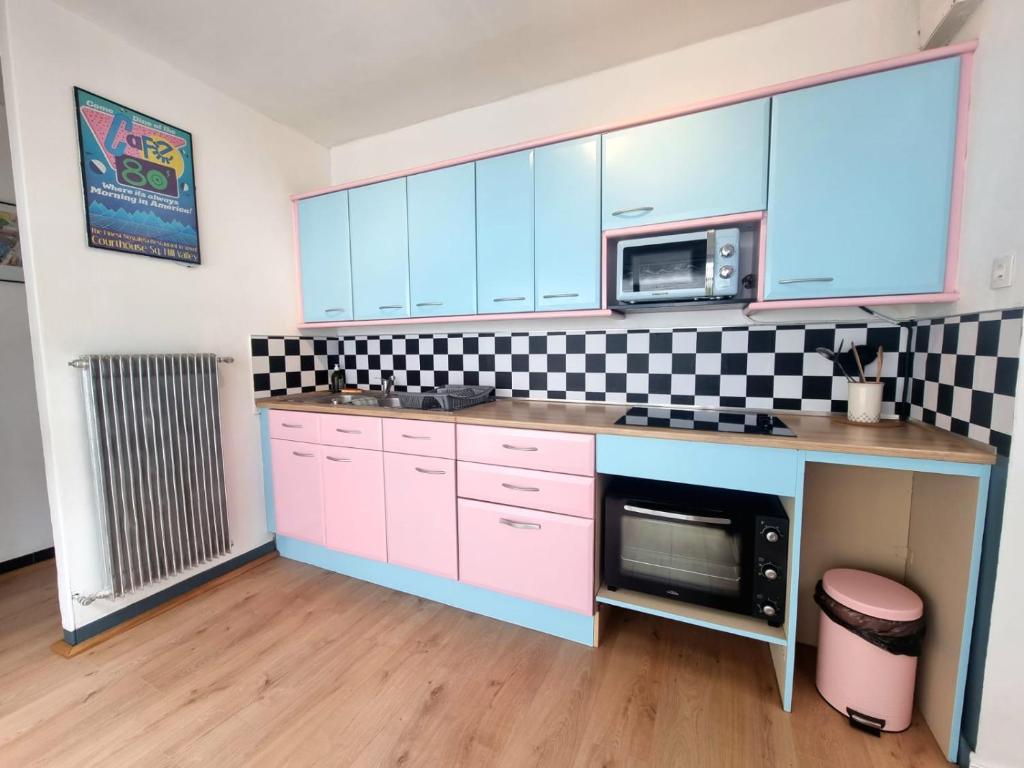 a kitchen with pink cabinets and a microwave at Le Mc Fly in Hénin-Beaumont