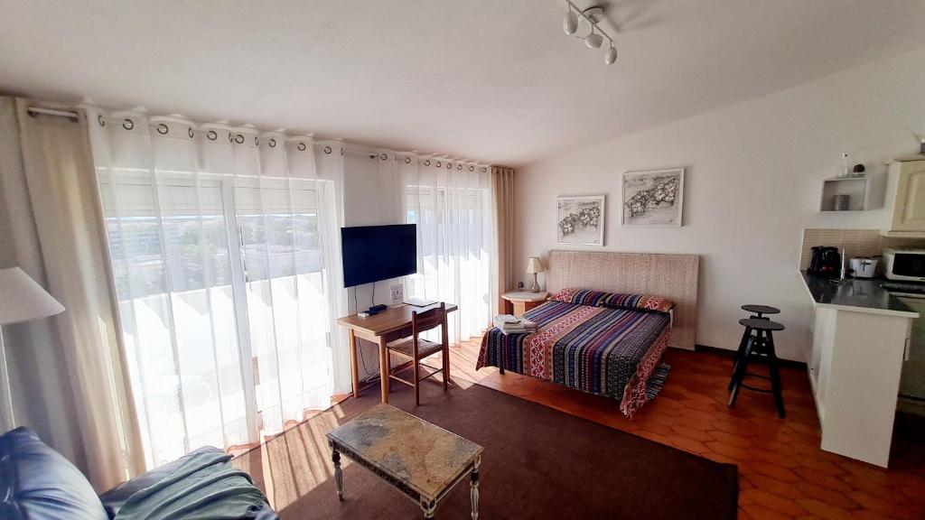 a living room with a couch and a television at Musa Mar studio with balcony panoramic view in the residential area in Quarteira