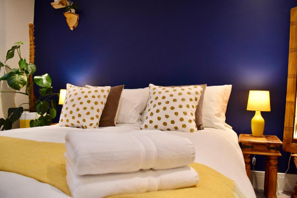 1 dormitorio con cama blanca y pared azul en Stylish centrally-located studio with parking, en Croydon