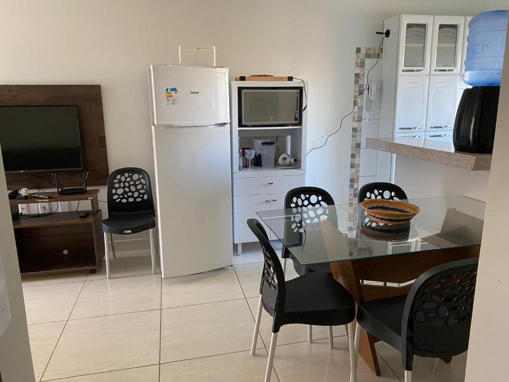 La cuisine est équipée d'une table à manger et d'un réfrigérateur blanc. dans l'établissement Apartamento 2 quartos a 300m da Praia, à Santa Cruz Cabrália