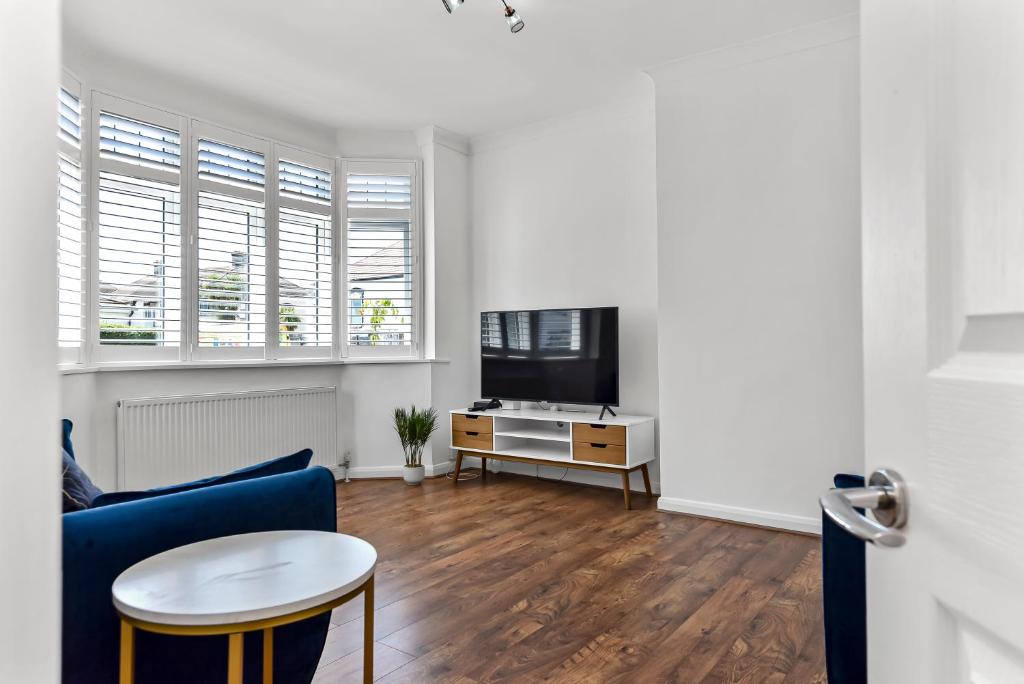 a living room with a blue couch and a tv at 3BR home/Fast Wi-Fi/ Quiet road in Hither Green