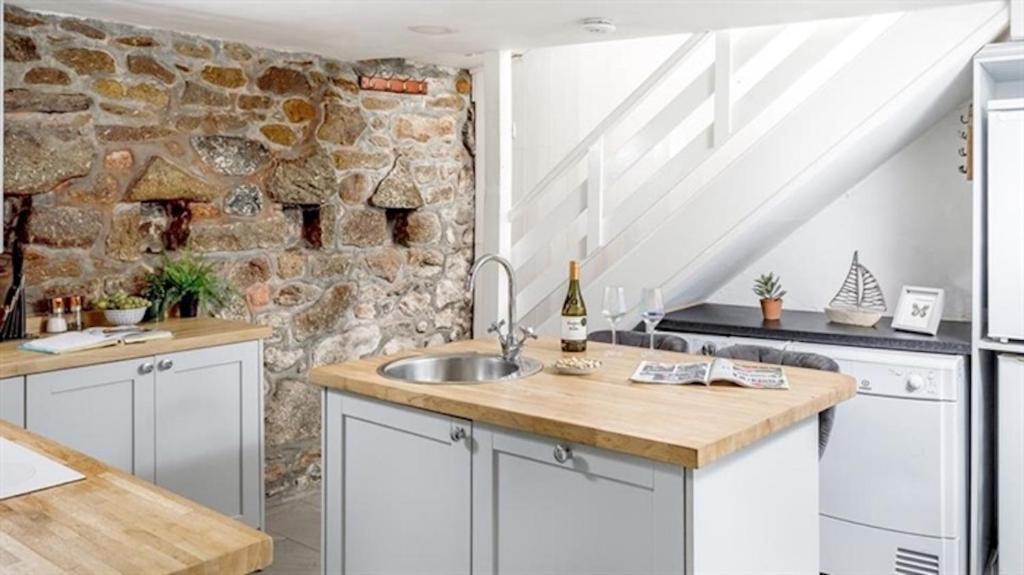 a kitchen with a sink and a stone wall at Boatsman's Cottage- sleeps 4- Garage- Mousehole in Mousehole