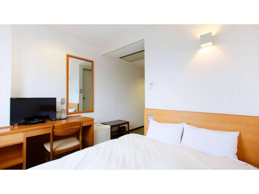 a bedroom with a bed and a desk and a television at Miyakonojo City Hotel - Vacation STAY 15150v in Miyakonozyō