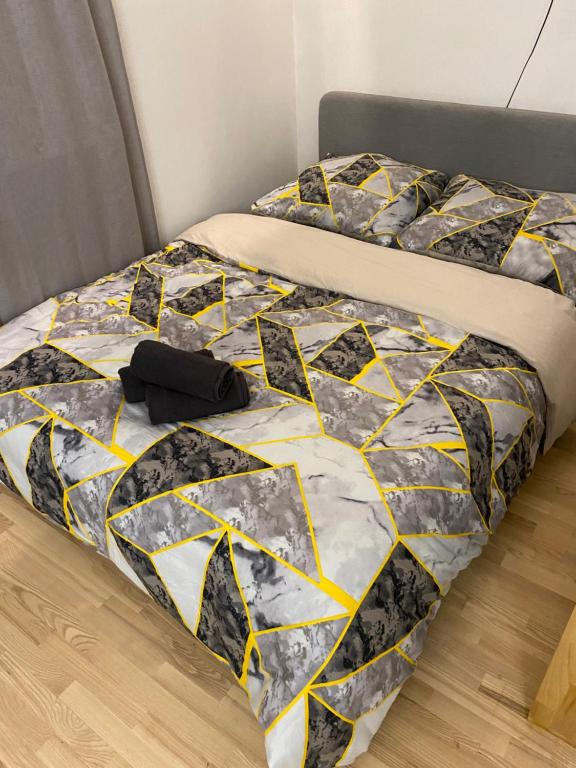 a bed with a black and yellow quilt on it at Love Glow Studio in Krakow