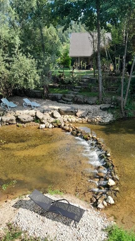 un río con algunas rocas y árboles y un edificio en River house - Riječna idila, en Cazin