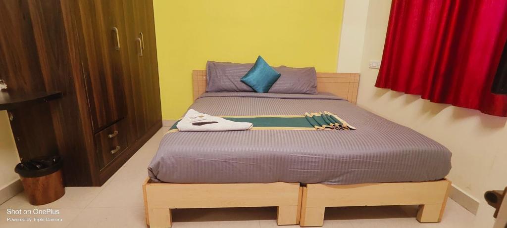 a small bed in a room with a red curtain at Hazel Inn Manyata in Bengaluru