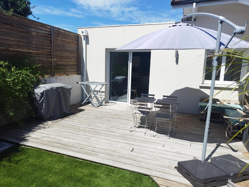 a wooden deck with chairs and an umbrella on a house at L'appartement des deux chênes in Capbreton