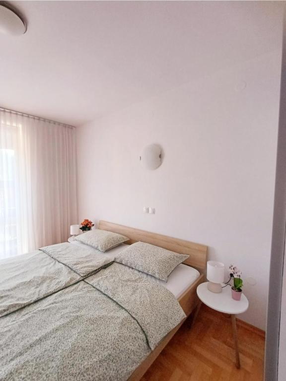 a white bedroom with a bed and a table at Apartma AJDA in Velenje