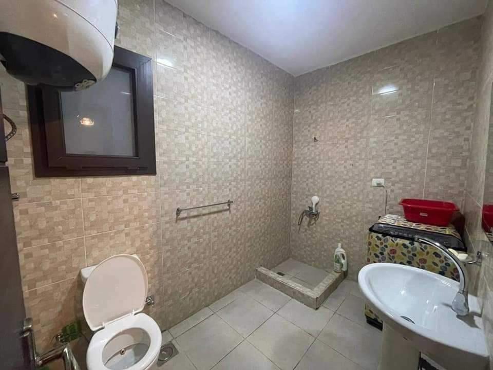 a bathroom with a toilet and a sink at Grand Hills in Al Ḩammām