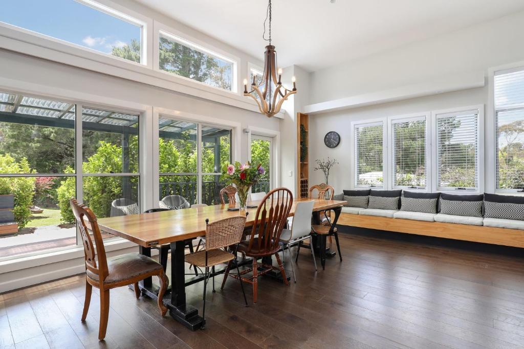 a dining room with a table and chairs and windows at Sofia Rose House and Cottage in Katoomba