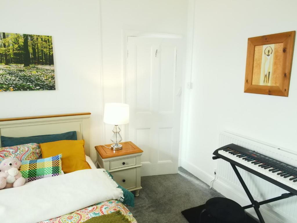 1 dormitorio con piano, cama y mesa en Enjoy Modern Living and Free WiFi in Kingston Newport 2 Bedroom Apartment en Newport