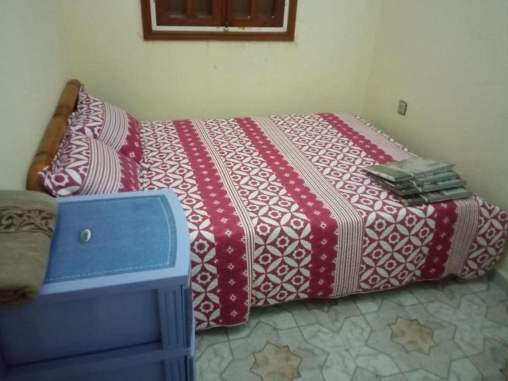 ein Bett mit einer roten und weißen Bettdecke in einem Schlafzimmer in der Unterkunft Appart centre in Larache
