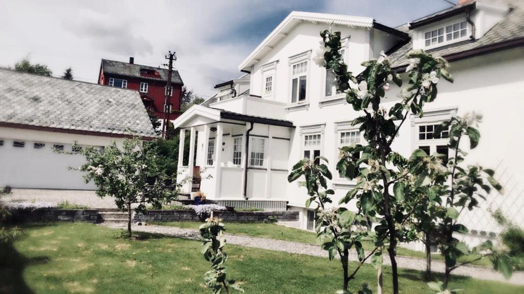 a white house with a person sitting on a bench in a yard at Bo i historisk bygning, kort vei til sentrum in Trondheim