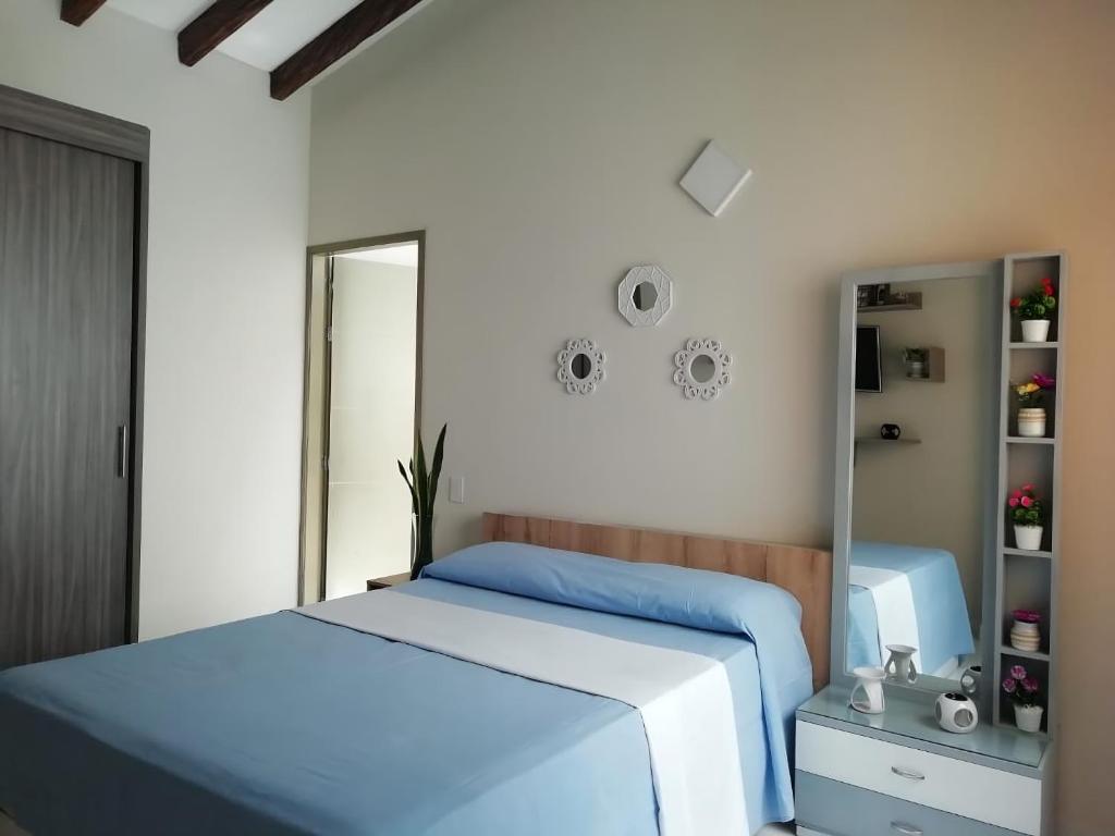ein Schlafzimmer mit einem blauen Bett und einem Spiegel in der Unterkunft ALAMEDA MI DESCANSO in Carmen de Viboral
