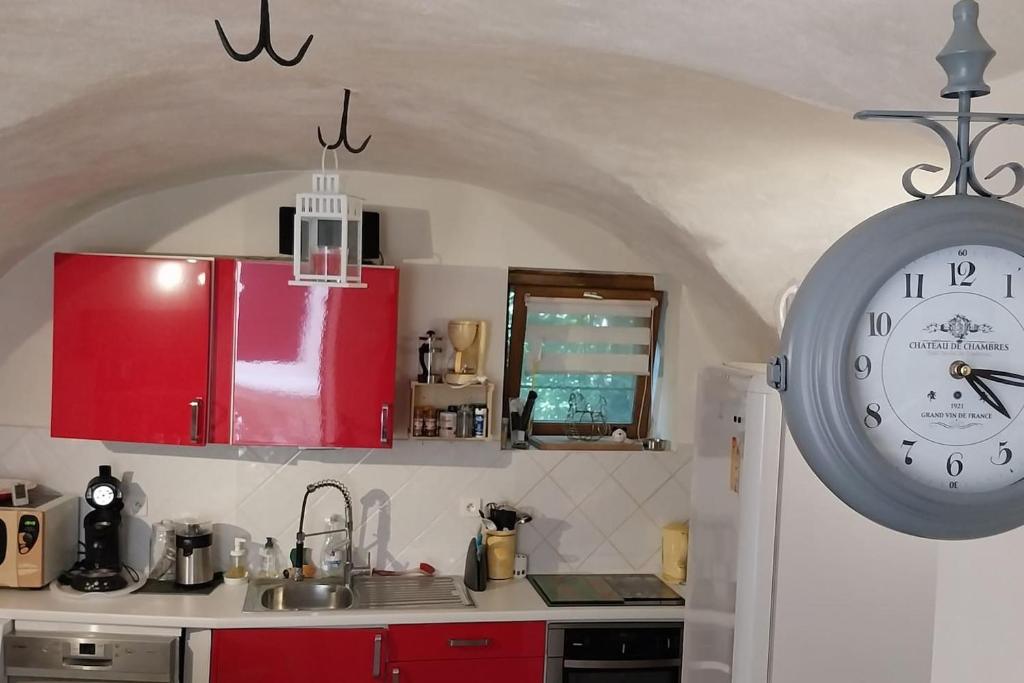 una cocina con armarios rojos y un reloj en la pared en A L ESCALE PASSA PAÏS, en Le Poujol-sur-Orb