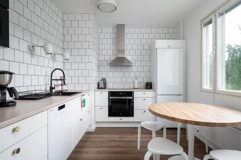 庫奧皮奧的住宿－Moderni ja tilava kolmio + sauna，厨房配有白色家电和木桌