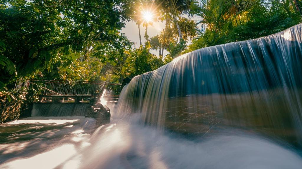 einen Wasserfall in einem Park neben einem Wasserfall in der Unterkunft Tabacón Thermal Resort & Spa in Fortuna