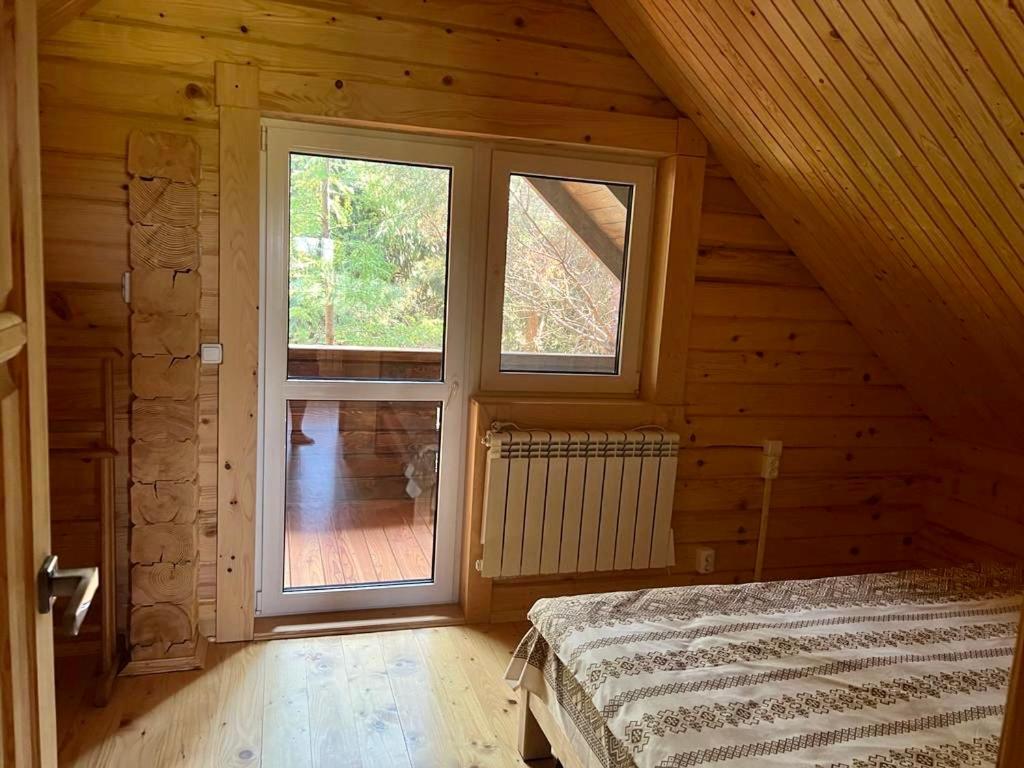 a bedroom with a large window in a log cabin at Family Resort in Mostiska