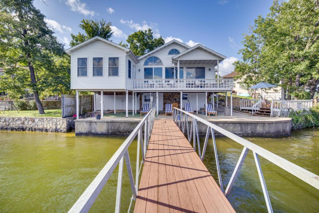 a white house on a dock in the water at Lake of the Ozarks Vacation Home with Boat Dock in Gravois Mills