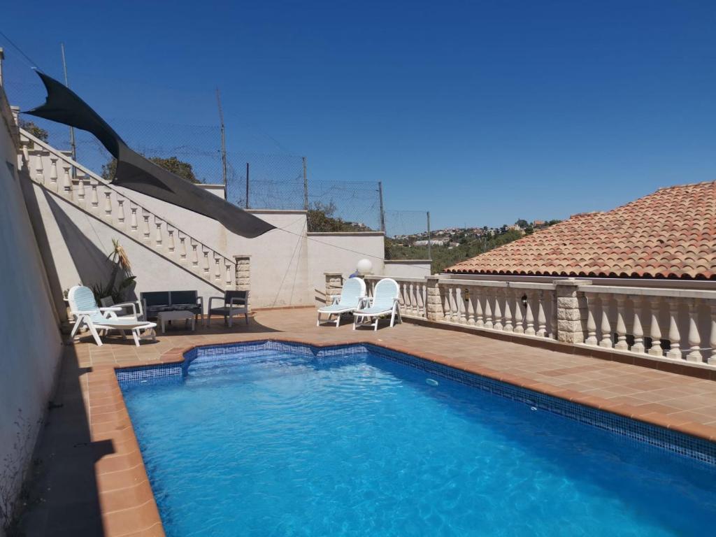 a swimming pool with two chairs and a house at CAN TRULLEN CHALET CALAFELL in Calafell