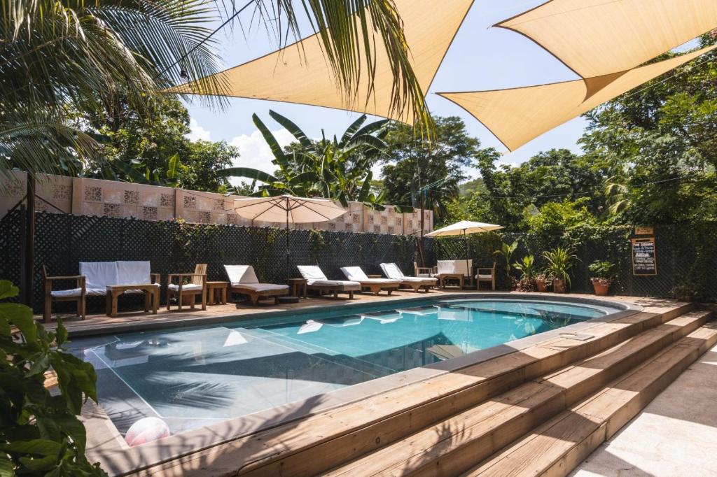uma piscina com cadeiras e um guarda-sol em Hotel Michanti em El Zonte