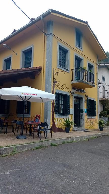 un edificio amarillo con mesas y sombrillas delante en Pension ILARRAZABAL en Azpeitia