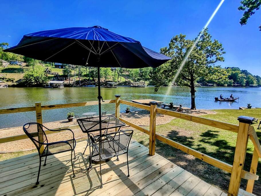 a table and chairs on a deck with an umbrella at #04-Adorable Large 1 Bedroom Lakeside Cottage- Pet Friendly in Hot Springs