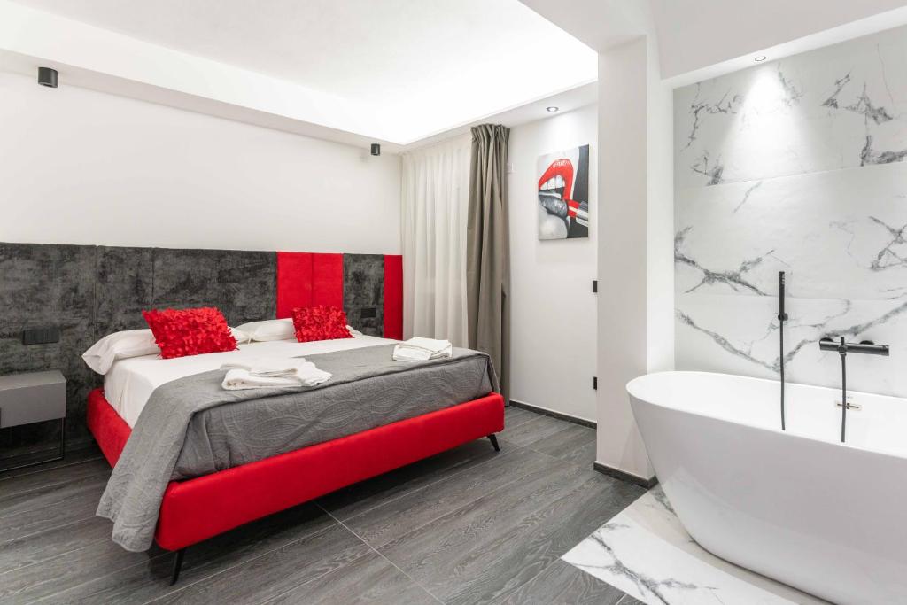 - une chambre avec un lit rouge et une baignoire dans l'établissement ML luxury room, à Lido di Spina